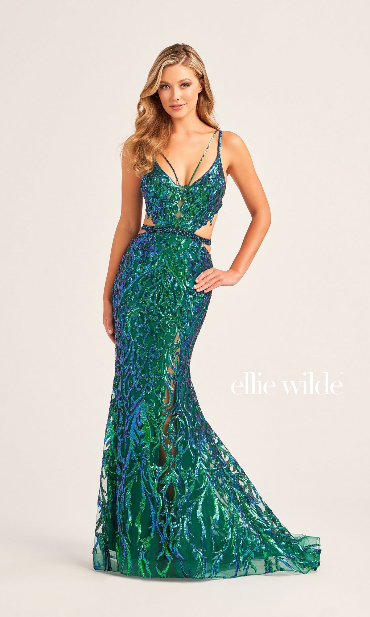 A woman poses in the Ellie Wilde Cut-Out Long Sequin Prom Dress EW35007, a floor-length fitted gown featuring green and blue sequins and cutout sides. A plain background displays the text